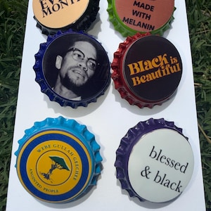 May include: Six bottle caps with diverse designs and text are displayed. The caps feature phrases such as "I'M BLACK EVERY MONTH" and "Black is Beautiful." Other caps display images and text related to Black culture and heritage.