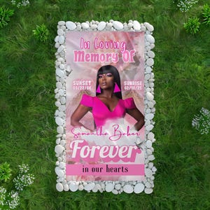 May include: A pink and white memorial plaque with a photo of a woman in a pink dress and angel wings. The text reads "In loving memory of Samantha Baker Forever in our hearts". The dates "Sunset 03/22/86 Sunrise 02/18/25" are also included.