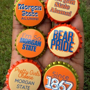 May include: Six metal bottle caps featuring orange and cream backgrounds with blue text. The caps display phrases including Morgan State Alumni, I'm So Morgan State, Bear Pride, Pretty Girls Choose Morgan State, and Since 1867 in various fonts.