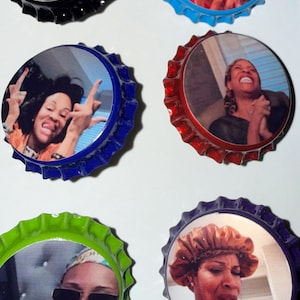 Könnte beinhalten: Sechs Flaschenverschluss-Magnete. Jeder Verschluss zeigt ein anderes Bild einer Frau mit unterschiedlichen Gesichtsausdrücken. Die Verschlüsse sind in verschiedenen Farben gehalten: Schwarz, Blau, Rot, Grün und Lila. Die Bilder sind auf der Innenseite der Flaschenverschlüsse gedruckt.