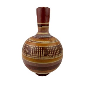 May include: A handcrafted, round ceramic vase with a narrow neck. The vase features a rich color palette of brown, tan, and burgundy horizontal stripes. Decorative vertical lines and shapes are etched around the body of the vase. The vase has a smooth, glossy finish.