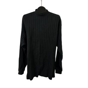 May include: A black ribbed knit long-sleeve shirt with a mock neck. The shirt is hanging on a black hanger against a white background. The fabric has vertical ribbing.
