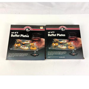 May include: Two boxes of "Cooks Tools" buffet plates, each containing a set of four. The boxes feature an image of a clear plastic serving tray with appetizers and a wine glass. The text on the box reads "Buffet Plates".
