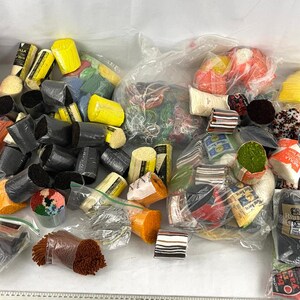 Könnte beinhalten: Eine große Sammlung von bunten Garnen und Stickgarnen in verschiedenen Schattierungen von Rot, Gelb, Blau, Grün und Weiß. Das Garn ist in Plastiktüten verpackt und einige sind mit Schnur gebunden.