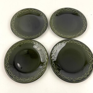Może przedstawiać: Zestaw czterech zielonych ceramicznych talerzyków deserowych z ozdobnym wzorem serca wokół krawędzi.
