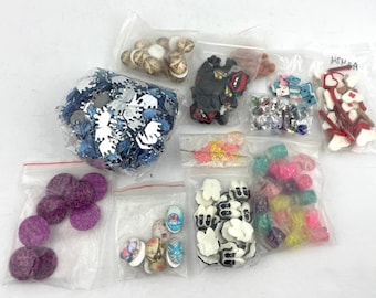 Puede incluir: Surtido de botones y adornos coloridos en bolsas de plástico transparentes. Los botones son de varias formas, tamaños y colores, incluyendo blanco, negro, rojo, azul, verde y amarillo. Algunos botones tienen un acabado brillante. Las bolsas están etiquetadas con el texto "HSN SA".