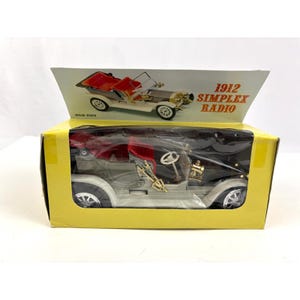 Puede incluir: Un coche modelo Simplex Radio de 1912 en una caja amarilla. El coche es negro con detalles dorados y un interior rojo. La caja tiene una imagen del coche y las palabras "1912 Simplex Radio". El coche es una réplica de un automóvil clásico.
