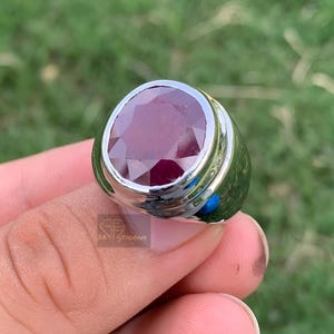 Peut inclure: Une bague en argent avec une grande pierre précieuse de rubis rouge foncé de forme ovale.