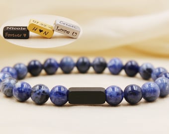 May include: A blue gemstone beaded bracelet with a black metal bead. The bracelet has three metal charms with engraved text: "Nicole Forever", "07.22 H ♥ N", and "Create Love U".