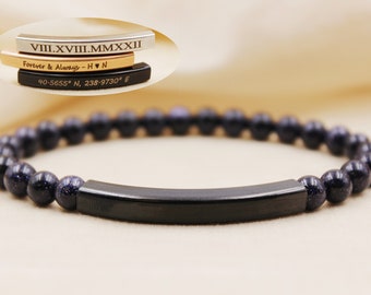 May include: A black beaded bracelet with a black metal bar engraved with the Roman numerals "VIII.XVIII.MMXXII", the text "Forever & Always - H ♥ N", and the coordinates "40-5655° N, 238-9730° E".