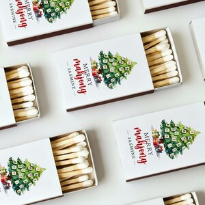 May include: White matchboxes with a Christmas tree design and the text "MERRY mahjong - JASMINE". The matches are visible inside the open boxes. The boxes have a brown border.