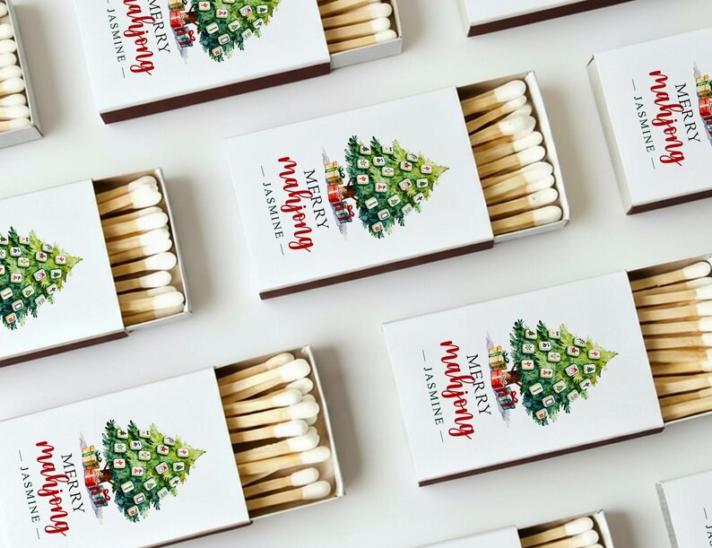 May include: White matchboxes with a Christmas tree design and the text "MERRY mahjong - JASMINE". The matches are visible inside the open boxes. The boxes have a brown border.