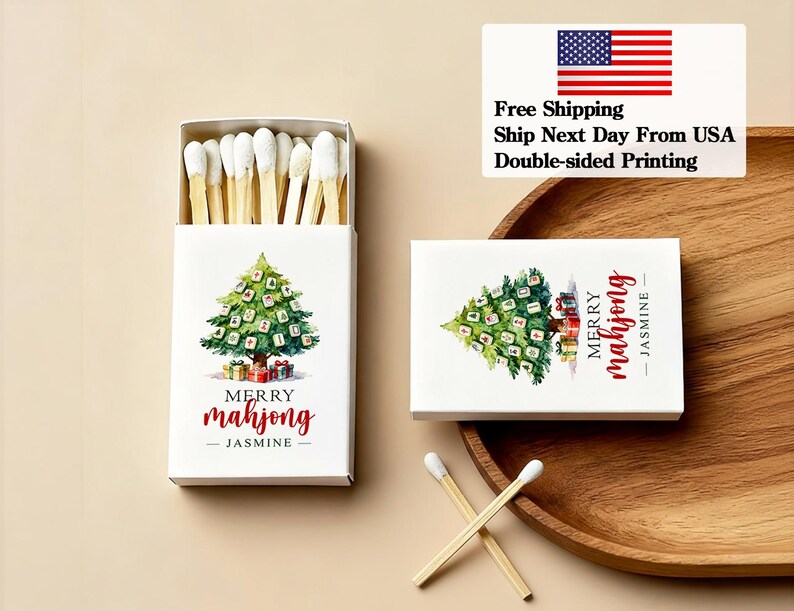 May include: White matchbox with a watercolor Christmas tree design, the text "Merry Mahjong - Jasmine" in red. The box is open, revealing matches with white tips. A second box and matches are also visible.