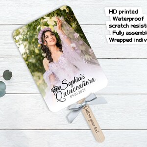 May include: A personalized fan featuring a photo of a woman in a lavender dress, with the text "Sophia's Quincea&ntilde;era 09.10.2025." The fan has a wooden handle with a gray ribbon and the text "Custom your text."