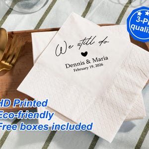 Könnte beinhalten: Weiße Papierservietten mit schwarzem Text, der "We still do" mit einem Herzsymbol, "Dennis & Maria" und "February 19, 2026" lautet. Die Servietten sind mit "HD Printed", "Eco-friendly" und "Free boxes included" bedruckt.