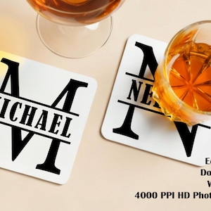 Può includere: Due sottobicchieri quadrati bianchi con scritte nere e un design con monogramma. Un sottobicchiere recita "MICHAEL" e l'altro "NE". Due bicchieri con liquido ambrato sono nell'immagine. I sottobicchieri sono ecologici, bifacciali e impermeabili.