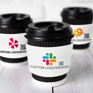 Könnte beinhalten: Drei schwarze Einweg-Kaffeebecher mit Deckeln, jeweils mit einer weißen Manschette mit individuellem Logo-Design. Die Logos sind in verschiedenen Farben gehalten, und der Text "CUSTOM LOGO/DESIGN" ist auf die Manschetten gedruckt. Ein QR-Code ist ebenfalls vorhanden.