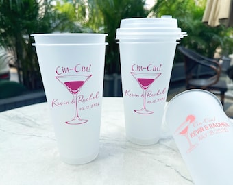Puede incluir: Tres vasos de plástico blancos con un diseño de copa de martini rosa y el texto "Cin-Cin! Kevin & Rachel" y la fecha del evento.