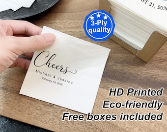 May include: A square white paper napkin featuring black printed text that reads Cheers, Michael & Jessica, and February 19, 2026. The napkin is 3-ply quality and comes with a brown cardboard box. The design includes a blue badge with 3-Ply quality text.