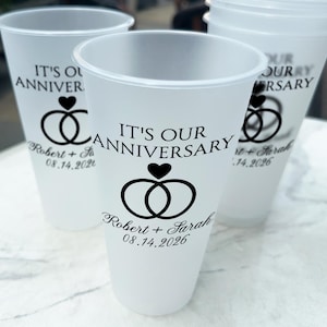 May include: White plastic cups with black text that reads "It's Our Anniversary" with a ring and heart design. The text also includes the names "Robert + Sarah" and the date "08.14.2026".