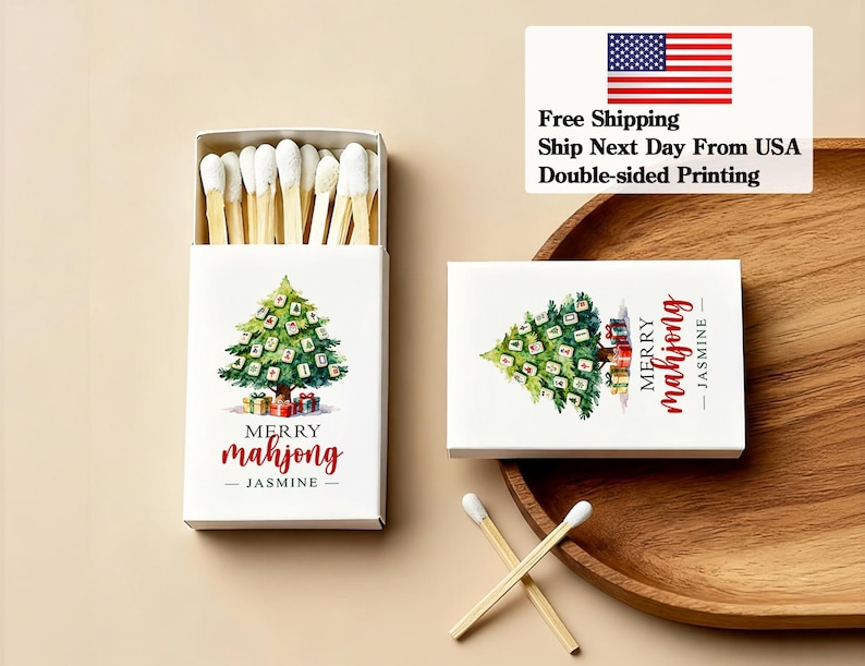May include: White matchbox with a watercolor Christmas tree design, the text "Merry Mahjong - Jasmine" in red. The box is open, revealing matches with white tips. A second box and matches are also visible.