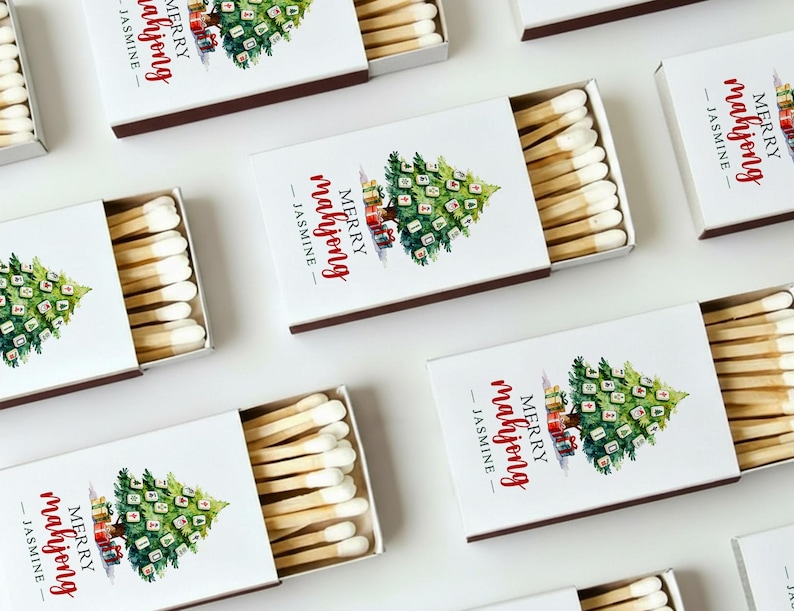 May include: White matchboxes with a Christmas tree design and the text "MERRY mahjong - JASMINE". The matches are visible inside the open boxes. The boxes have a brown border.