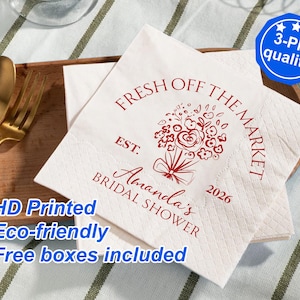 Puede incluir: Servilletas de papel blancas con texto rojo que dice "Fresh Off The Market" y "Amanda's Bridal Shower" con un diseño floral y el año 2026. Las servilletas están impresas con "HD Printed Eco-friendly Free boxes included".