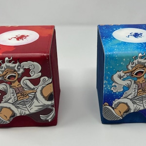 May include: Two square-shaped deck boxes with a cartoon character on each. The box on the left is red with a white character and white clouds. The box on the right is blue with a white character and white clouds.
