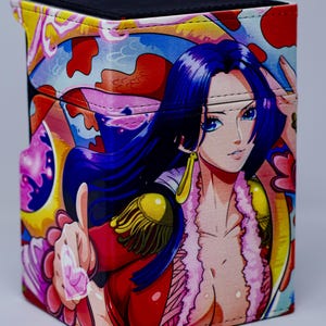 May include: A colorful card deck box featuring a female anime character with long blue hair, wearing a red and pink outfit. The box has a black top and is decorated with a floral pattern.