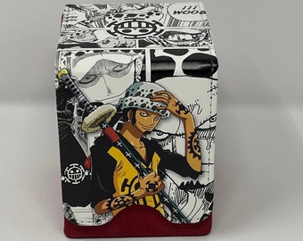 May include: A black and white deck box featuring a manga style illustration of a character with a sword and a skull and crossbones symbol. The box has a red base.