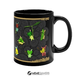 Puede incluir: Taza de caf&eacute; de cer&aacute;mica negra con un dise&ntilde;o de personajes de dibujos animados verdes, rojos y amarillos sobre un fondo negro y dorado. Los personajes est&aacute;n rodeados de c&iacute;rculos conc&eacute;ntricos.