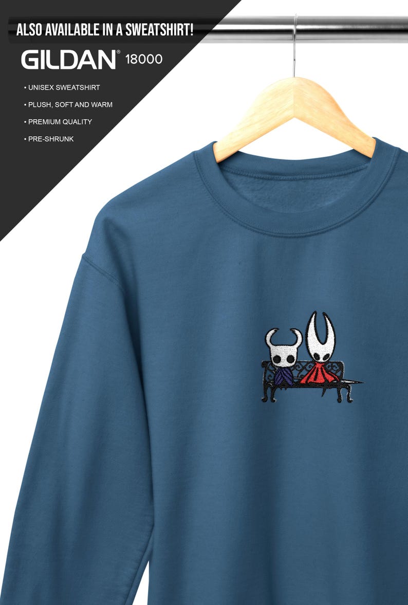 Pode incluir: Uma camisola azul de gola redonda com um bordado de duas personagens de m&aacute;scara branca sentadas num banco preto. O texto "ALSO AVAILABLE IN A SWEATSHIRT! GILDAN 18000 UNISEX SWEATSHIRT PLUSH, SOFT AND WARM PREMIUM QUALITY PRE-SHRUNK" &eacute; vis&iacute;vel.