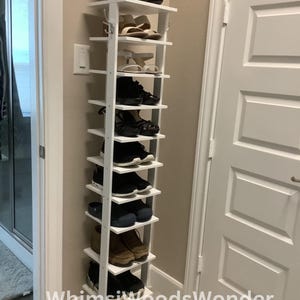 May include: White shoe rack with 10 shelves, holding a variety of shoes, including boots, sandals, sneakers, and dress shoes. The rack is labeled "Whims Woods Wonder".