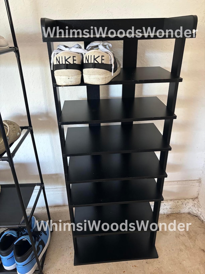 May include: Black shoe rack with six shelves. The top shelf has two white sneakers with black Nike logos. The shoe rack is labeled "Whims Woods Wonder".