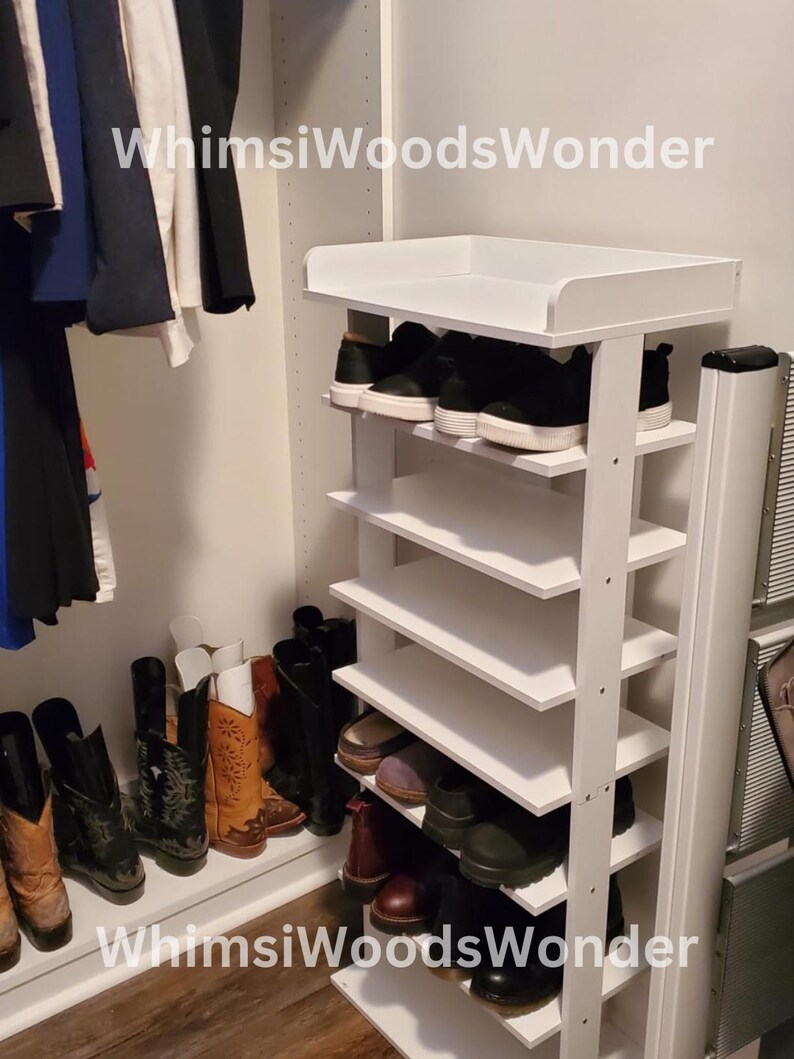 May include: White shoe rack with six shelves, filled with shoes. The rack is in a closet with a white wall and a wooden floor. The text "WhimsWoodsWonder" is visible on the rack.