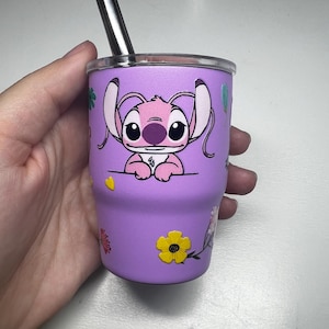 Puede incluir: Un vaso morado con un personaje de dibujos animados, una pajita plateada y decoraciones florales. El vaso est&aacute; dise&ntilde;ado para bebidas fr&iacute;as. El vaso mide unos 10 cm de alto.