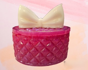 Könnte beinhalten: Eine dekorative Schatulle in Rosa und Weiß mit gestepptem Design und einer weißen Schleife oben.