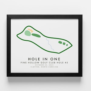 May include: A green and white illustration of a golf course hole with the text "HOLE IN ONE PINE HOLLOW GOLF CLUB HOLE #5 OCTOBER 22, 2023 CLAYTON, NORTH CAROLINA"