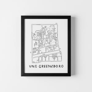 Op de afbeelding: Zwart ingelijste print met een gedetailleerde zwart-wit kaart van een universiteitscampus. De tekst "UNC GREENSBORO" is in een eenvoudig lettertype onderaan afgedrukt. De print wordt tegen een witte muur getoond.