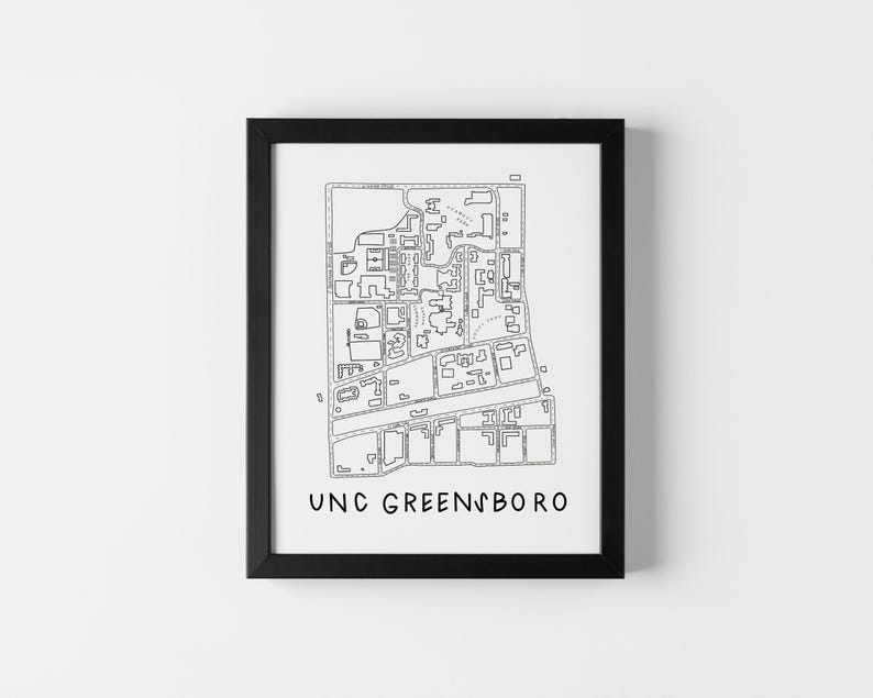 Op de afbeelding: Zwart ingelijste print met een gedetailleerde zwart-wit kaart van een universiteitscampus. De tekst "UNC GREENSBORO" is in een eenvoudig lettertype onderaan afgedrukt. De print wordt tegen een witte muur getoond.