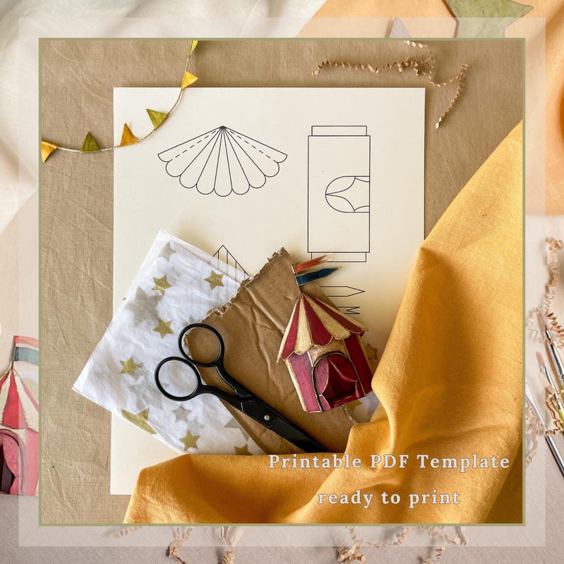 May include: A still-life image featuring a printable PDF template with circus-themed designs. The composition includes a sheet with line drawings, a small circus tent, scissors, and fabric. The text "Printable PDF Template ready to print" is visible.