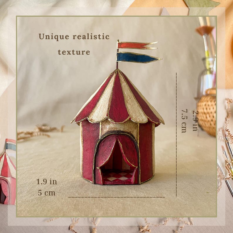 May include: A miniature circus tent, 1.9 inches (5 cm) wide and 2.9 inches (7.5 cm) tall, with red and cream stripes, a gold trim, and a red arched doorway. The tent has two small flags with red and blue accents. The text "Unique realistic texture" is visible.
