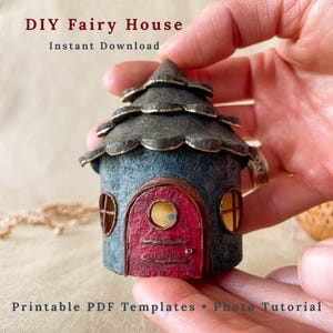 May include: A miniature DIY fairy house with a dark textured exterior, a red arched door, and a multi-tiered roof with gold-painted edges. The structure features two small circular windows and includes the text DIY Fairy House Instant Download.
