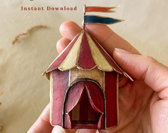 May include: A miniature circus tent model featuring red and cream vertical stripes, a scalloped roof edge, and a dual-colored flag topper in red and blue. The text Vintage Circus DIY, Instant Download, Printable PDF Templates, Photo Tutorial is visible.