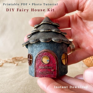 May include: A miniature fairy house kit with the text "Printable PDF • Photo Tutorial DIY Fairy House Kit Instant Download". The house is blue with a red door and gold accents. The roof is dark grey with gold trim.