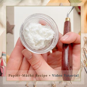 May include: A clear glass jar filled with white, textured material, held in a person's hand. A painting knife with a wooden handle is held nearby. The text "Papier-Mache Recipe + Video Tutorial" is at the bottom of the image.
