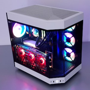 May include: A white and black computer case with a glass side panel, displaying internal components lit by colourful LED lights. The case has a Radeon graphics card with red fans and cooling fans.