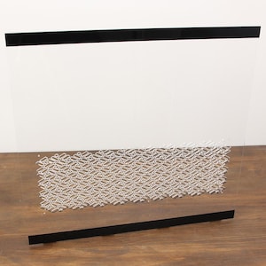 May include: A rectangular clear acrylic fireplace screen featuring a horizontal black border at the top and bottom edges. The center section of the transparent panel displays a repeating geometric pattern of small, silver-colored rectangular cutouts.