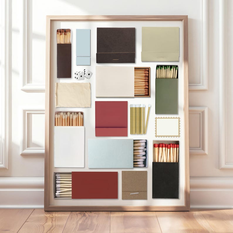May include: A framed collection of various matchboxes in different colors, including brown, blue, red, and green. Some boxes are open, revealing the matches inside. Two dice are also included in the arrangement. The matches have red or green tips.