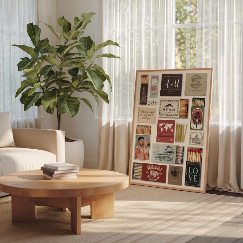 May include: A framed display featuring various vintage-style matchboxes and postcards. The display includes a photo and text, with a wooden frame. A large potted plant and a round wooden coffee table are in the foreground.